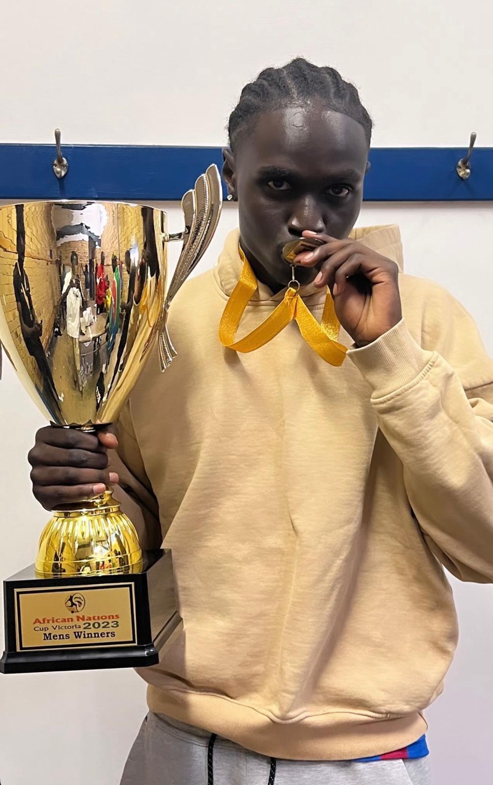 Aguer holding a football trophy and wearing a winner’s medal